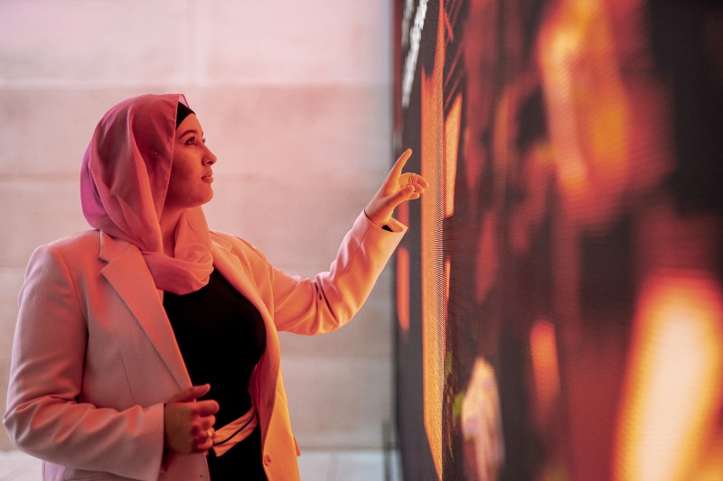a woman interacts with a large touch screen